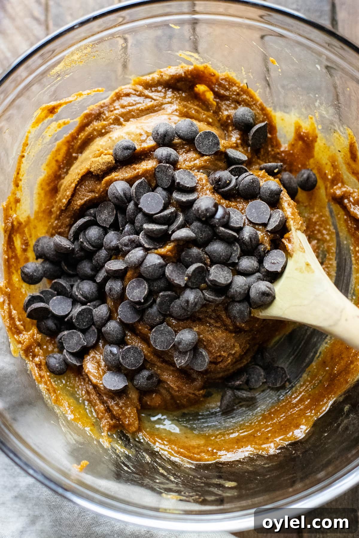 Flourless Chocolate Chip Cookies That Stay Chewy 6 chocolate chips being stirred into cookie batter with wooden spoon.