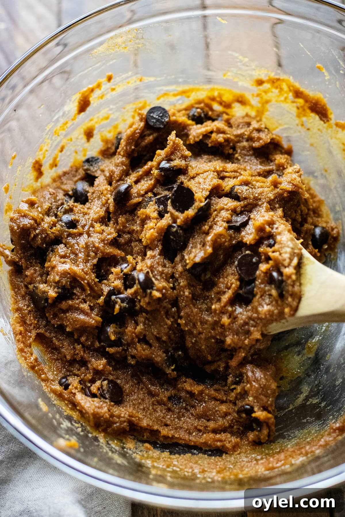 Flourless Chocolate Chip Cookies That Stay Chewy 7 cookie dough in clear glass bowl with wooden spoon.