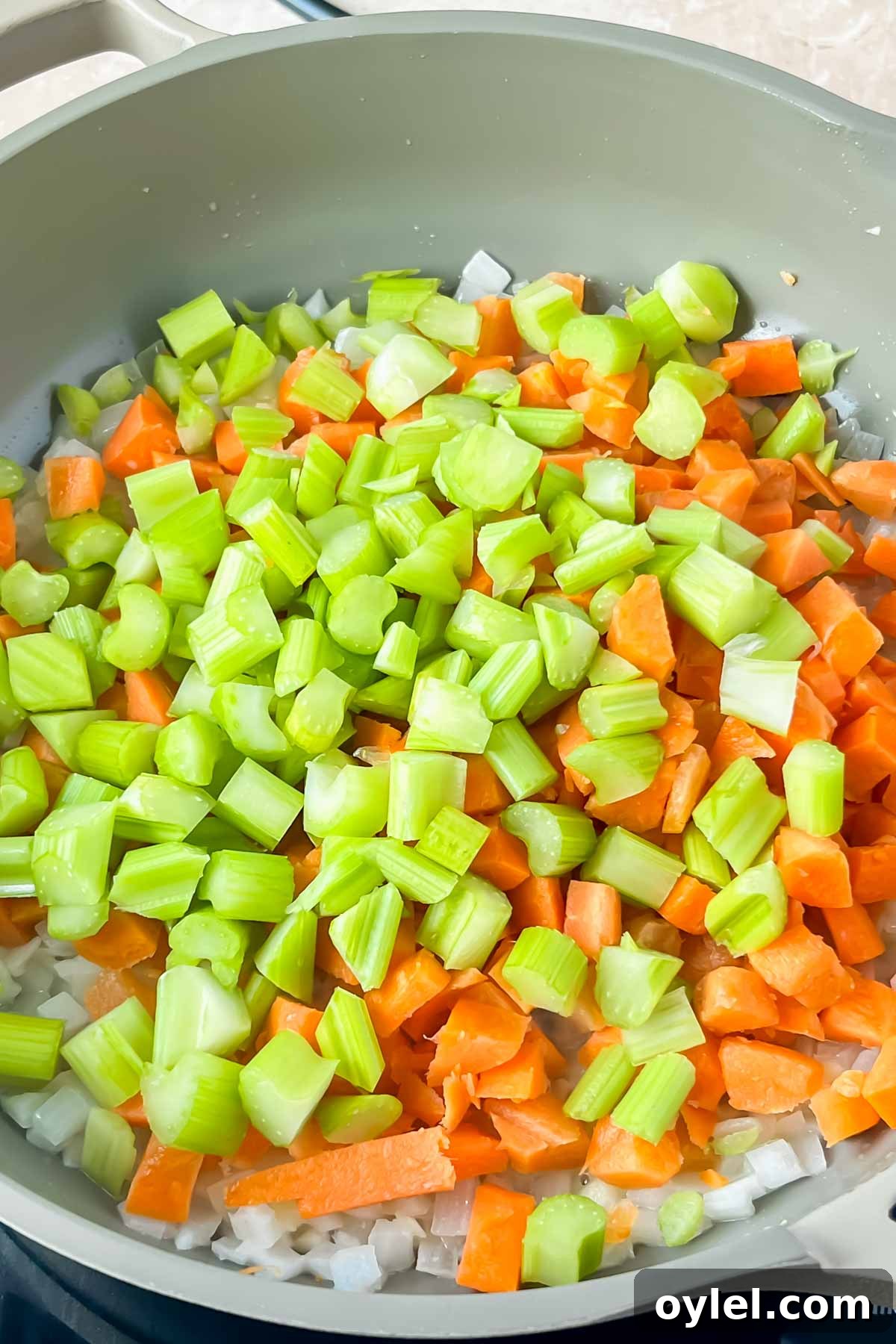 onions, carrots, and celery in gray skillet.