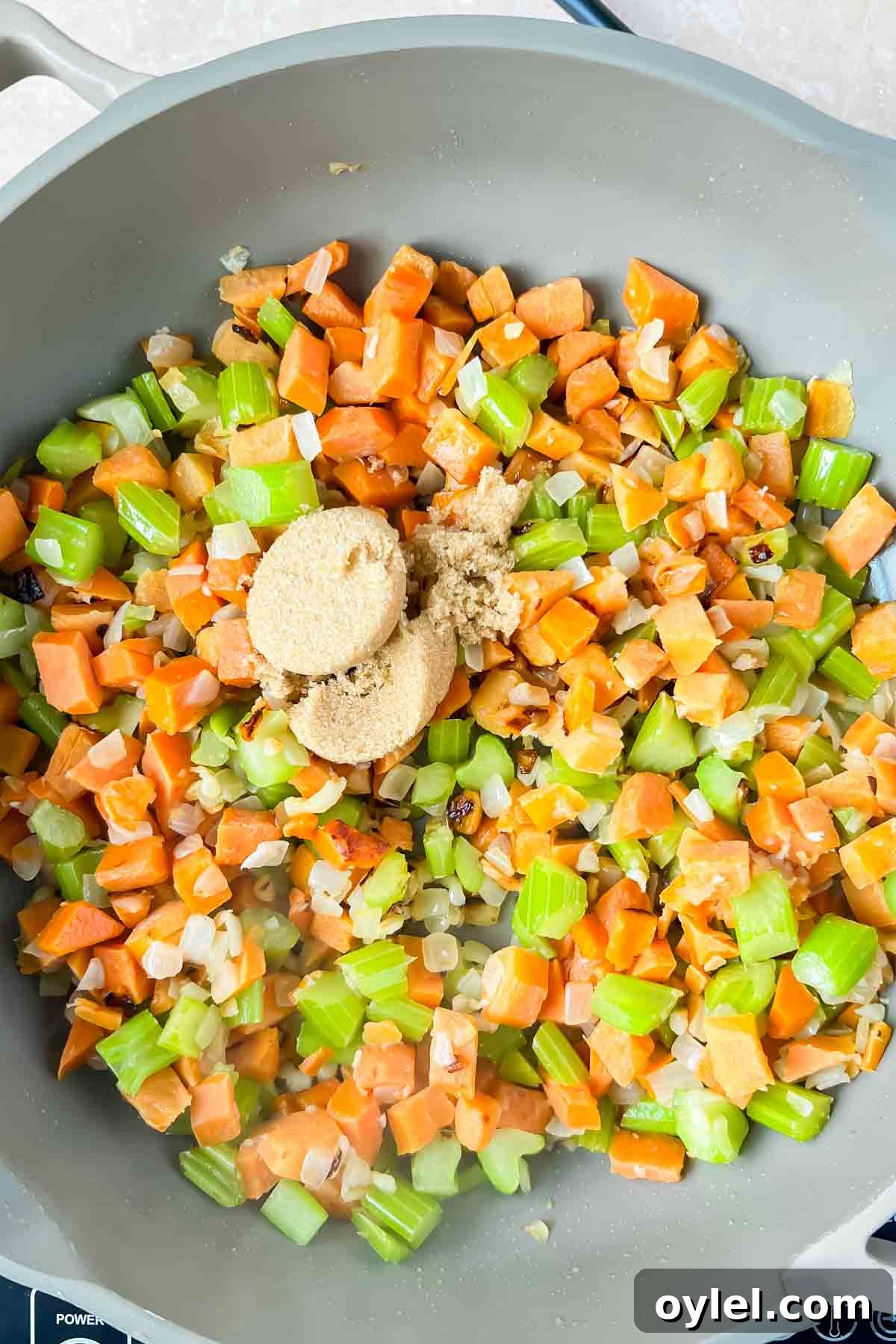 onions, carrots, and celery in gray skillet.