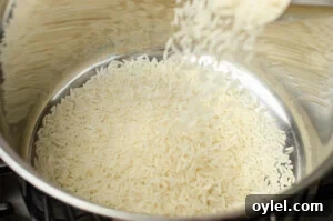 Authentic Jasmine Sticky Rice Recipe from Thailand 4 Jasmine rice being poured into a silver cooking pot