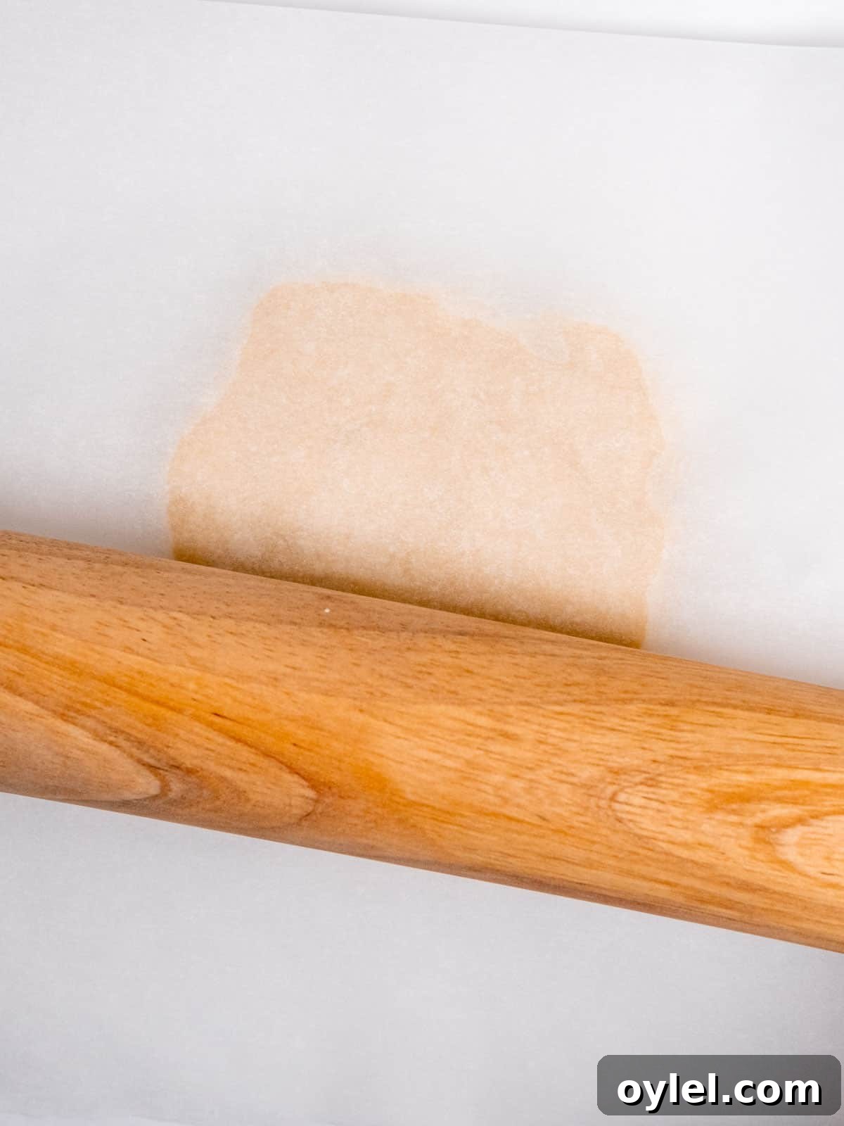 Pressing a rolling pin over pie dough flattened between sheets of parchment paper.