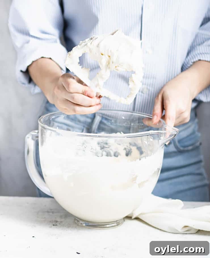 hand holding a beater with frosting on it