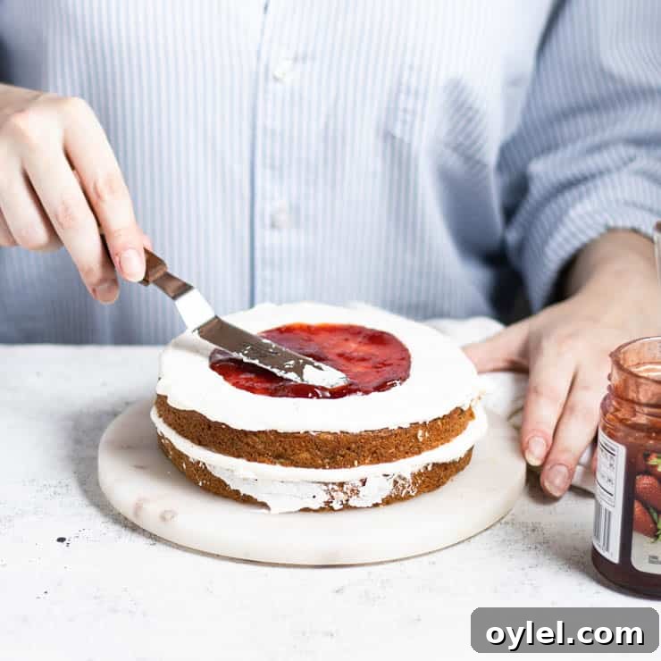 jam being spread in the center of a layer of cake