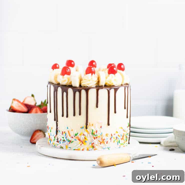 frosted banana split cake in front of a stack of plates and a bowl of strawberries