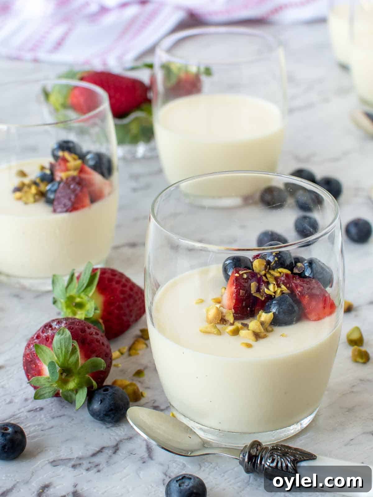 An Italian Panna Cotta Recipe set in glasses with strawberries and blueberries.