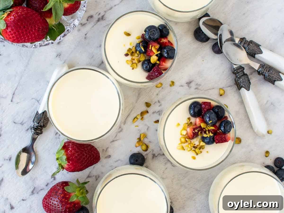 Vanilla panna cotta in glasses with strawberries and blueberries viewed from above.