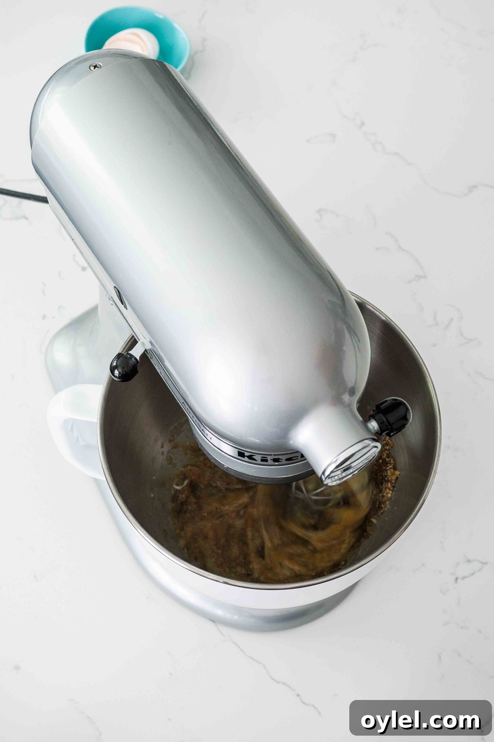 A stand mixer whisks together brown sugar and eggs.