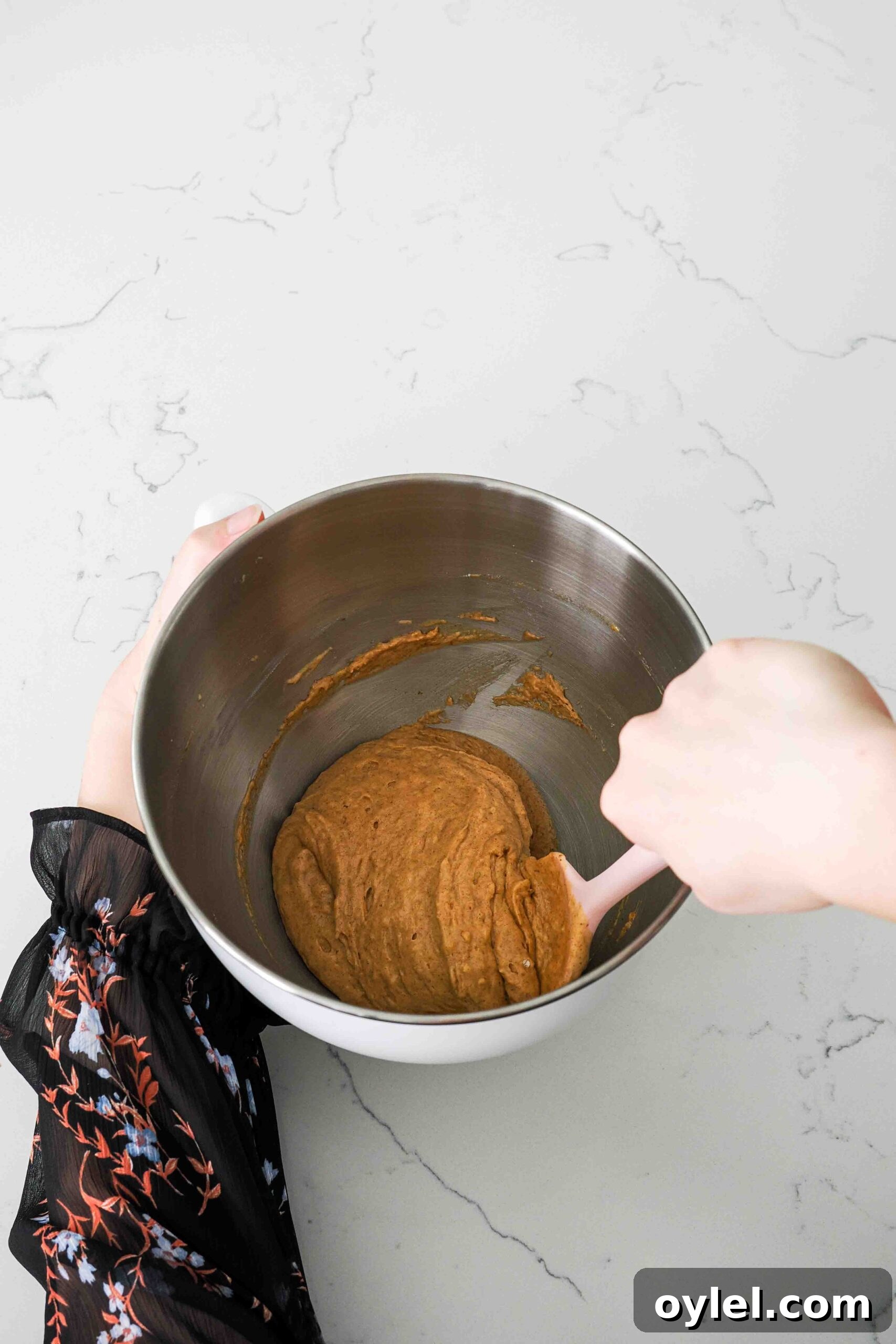 A spatula finishes folding together pumpkin madeleine batter without butter.
