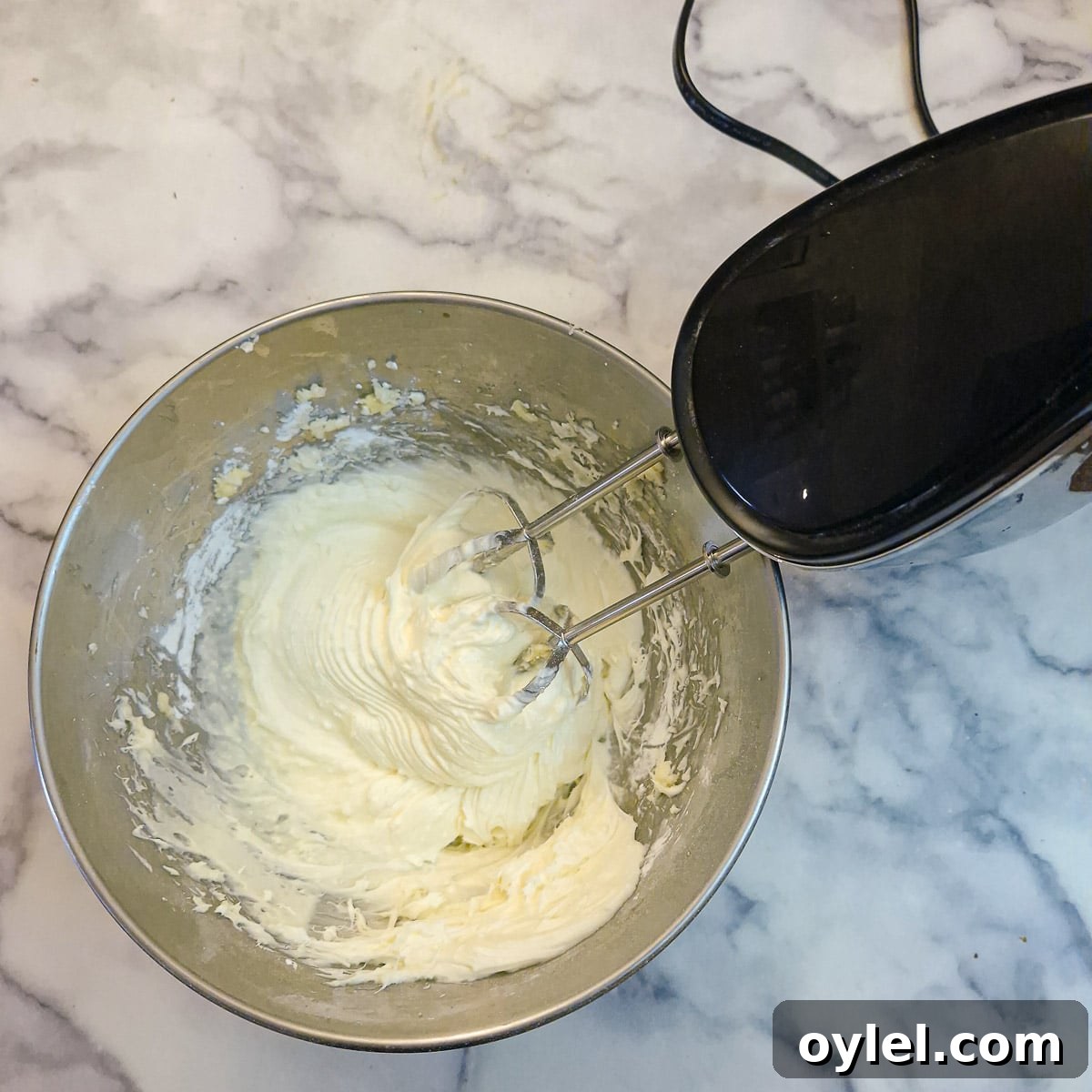 Cream cheese frosting being whipped in a mixing bowl.