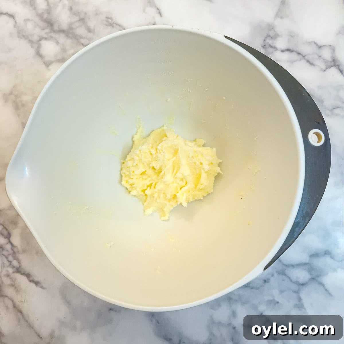Butter and sugar creamed until light and fluffy in a white mixing bowl.