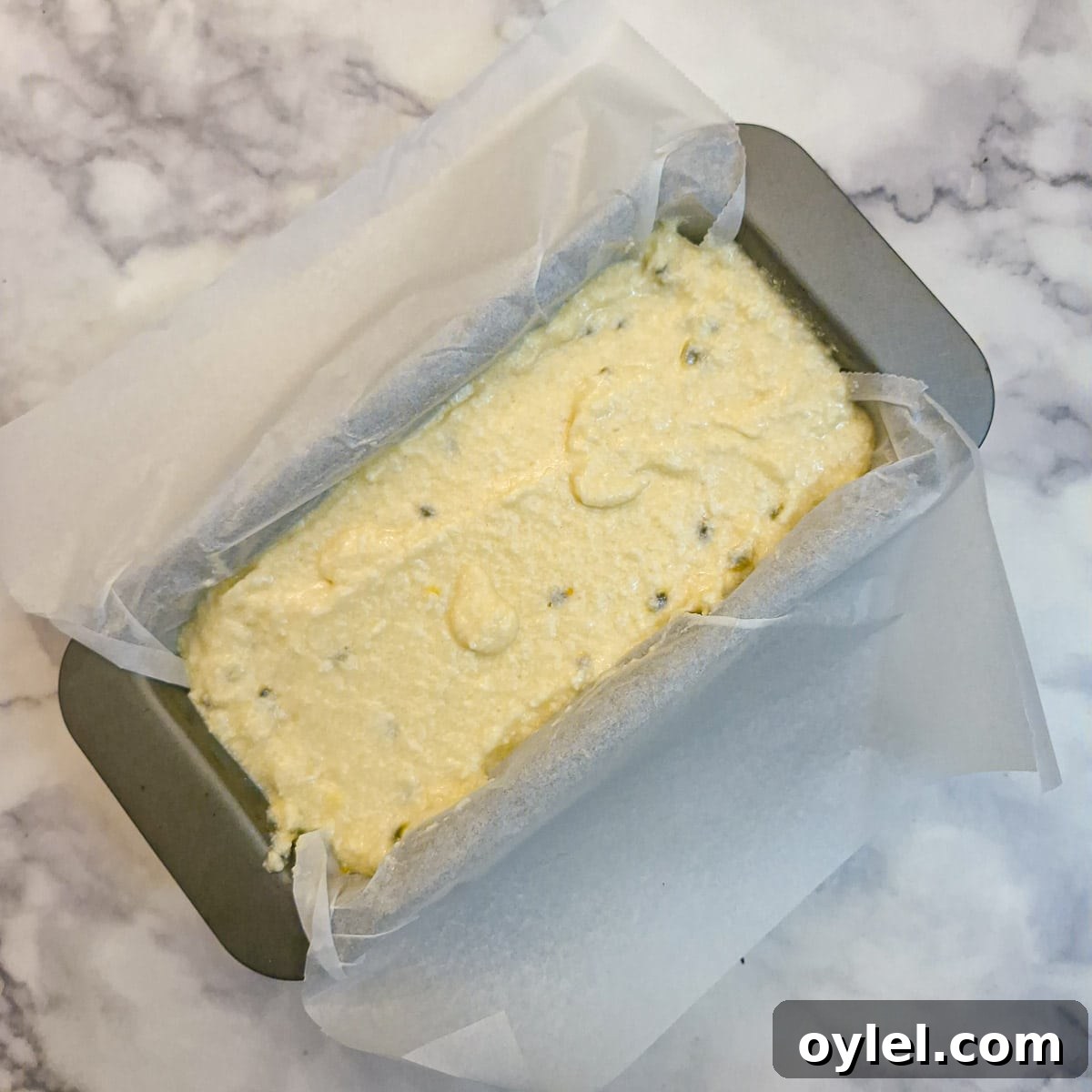 The cake batter in a lined cake tin before baking.