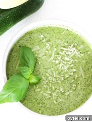 Zucchini pesto in a white bowl topped with fresh basil leaves.