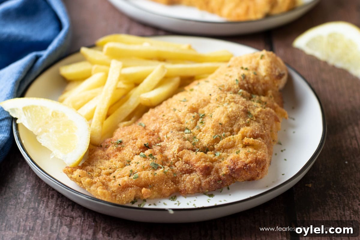 A piece of gluten free air fried catfish on a white plate.