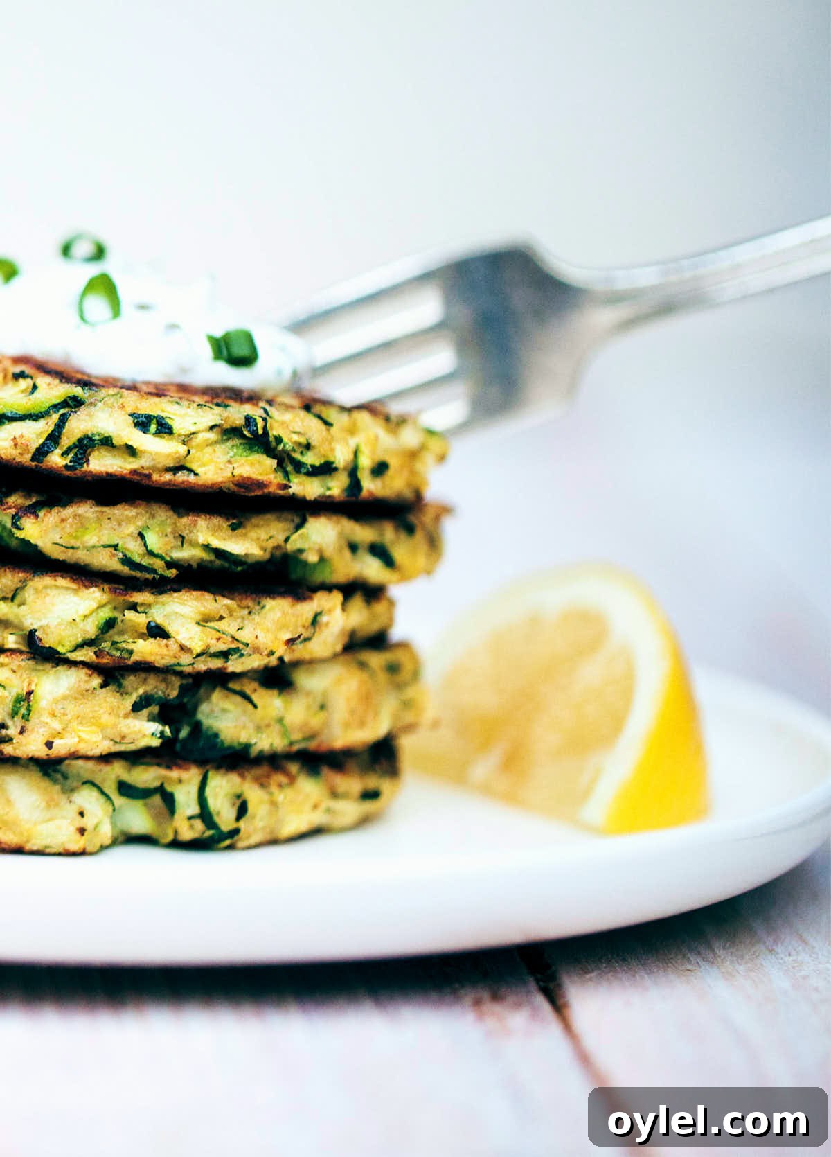 Digging into zucchini fritters topped with dill yogurt sauce