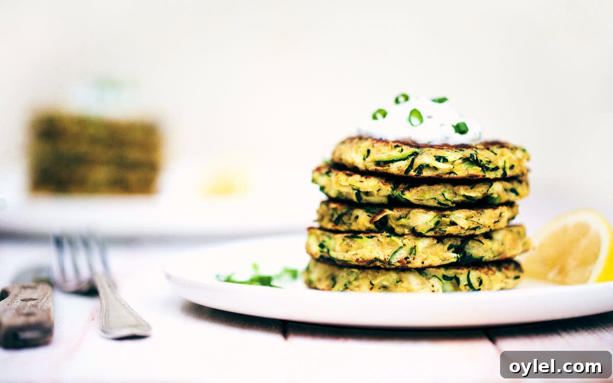 Side view of zucchini fritters on a white plate