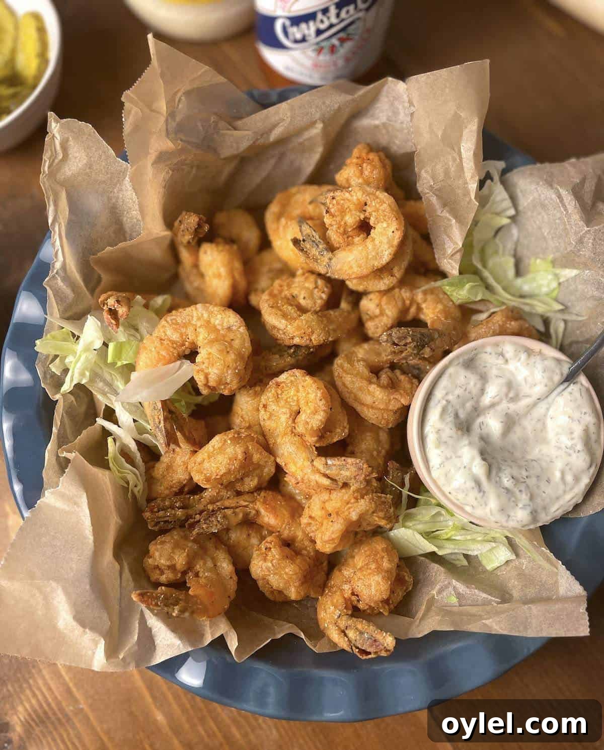 A blue bowl of southern fried shrimp with tartar sauce and shredded lettuce.
