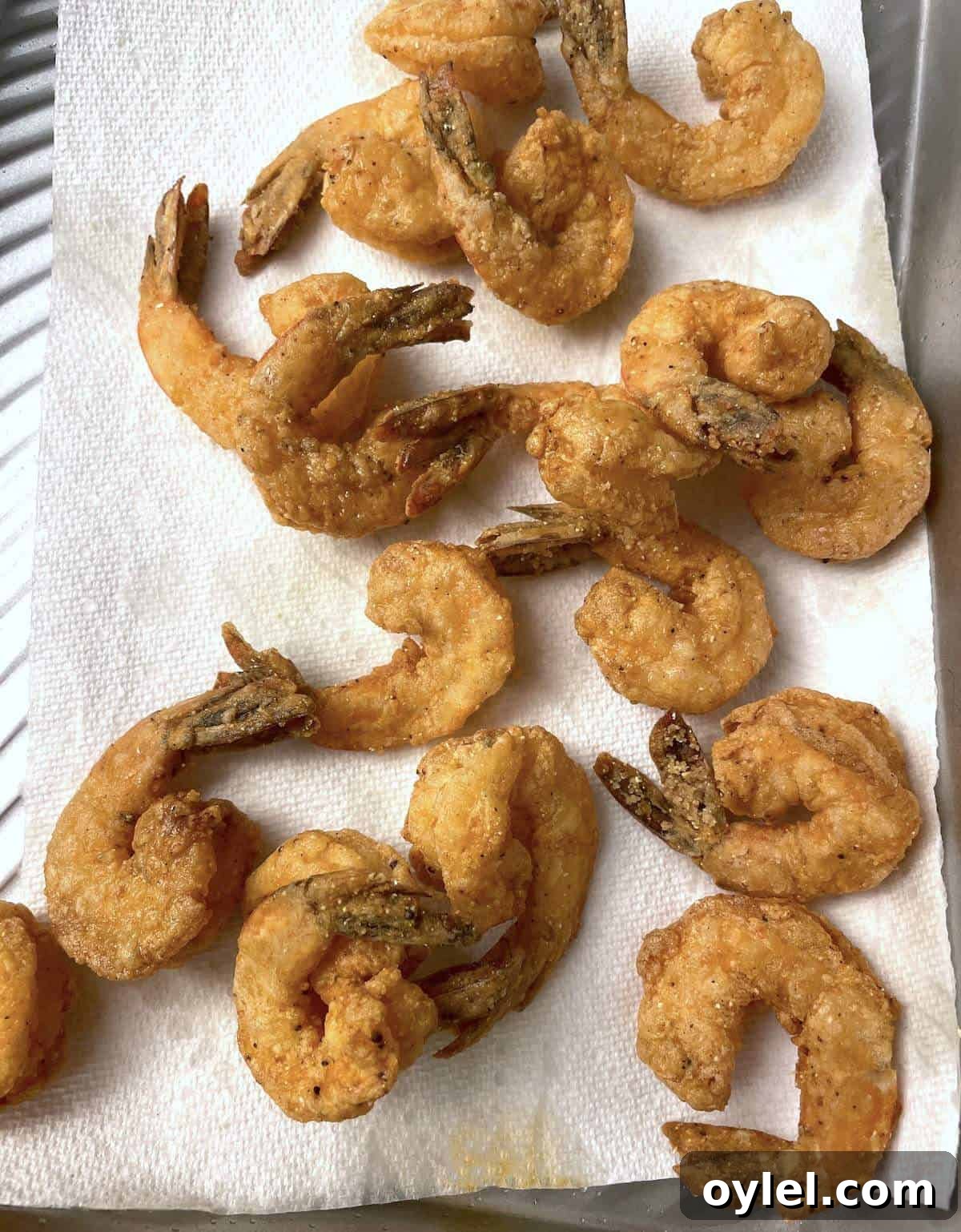 Deep fried shrimp draining on a paper towel.