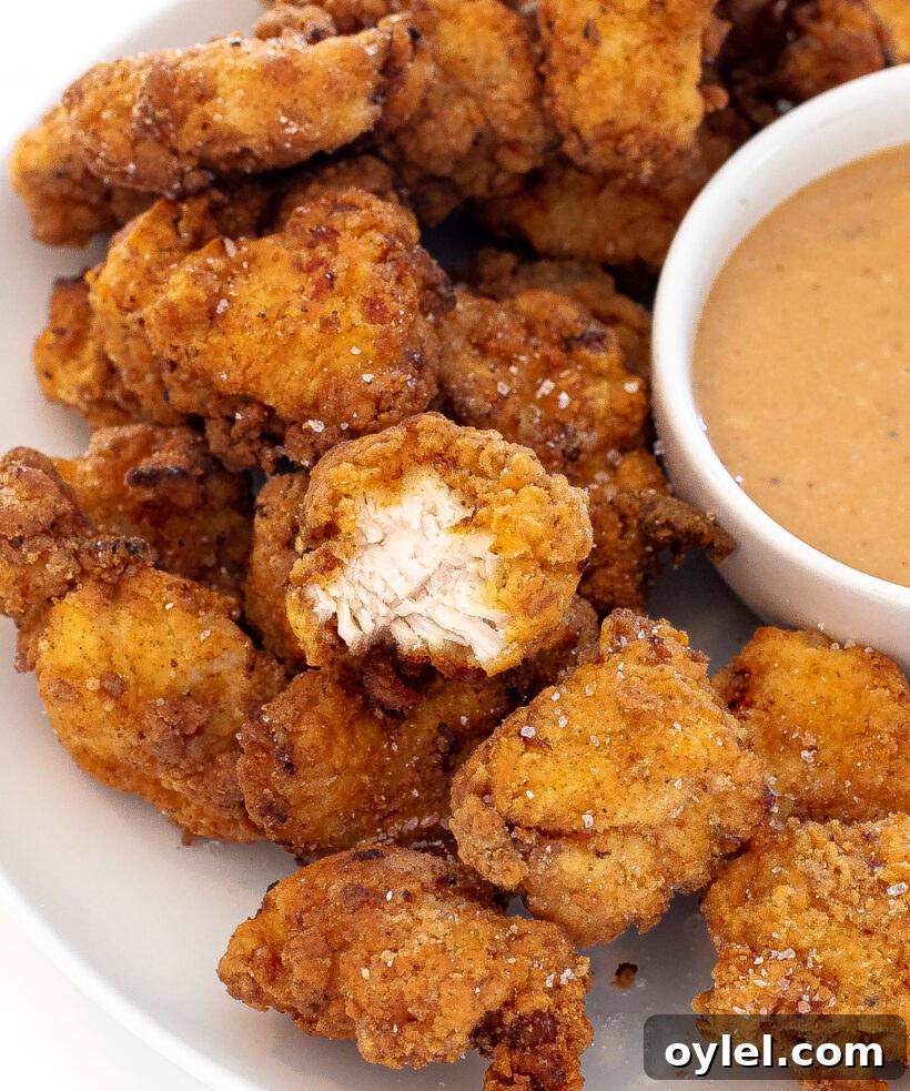 Chick fil a nuggets on a serving plate with a side of sauce next to them.