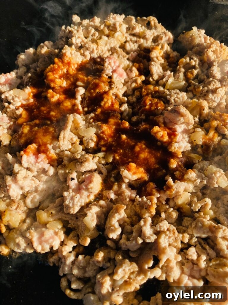 Talking meat on the Blackstone after Browning and adding the sauce
