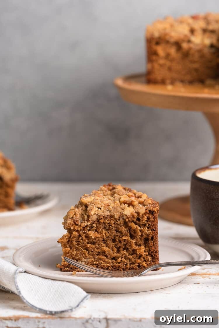 Authentic Spanish Coffee Cake Recipe 5 A slice of Spanish Coffee Cake on a cream plate with a cup of coffee.