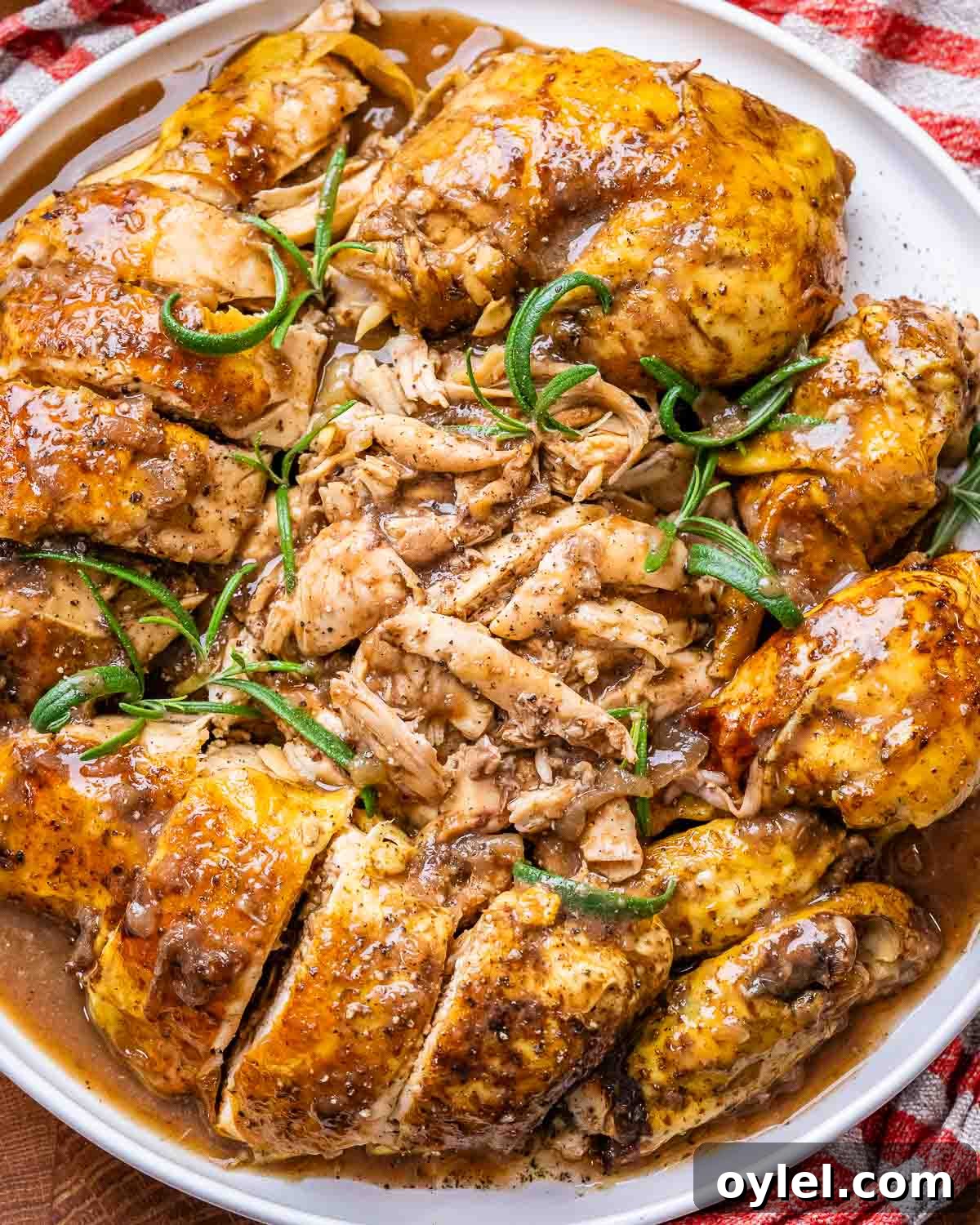 Balsamic Chicken with Caramelized Onions and Garlic 10 Pieces of balsamic chicken that have been sliced up and placed on a white plate, then sprinkled with pepper and sprigs of rosemary.