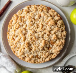 Irish apple cake with crumble topping on a plate next to Granny Smith apples.