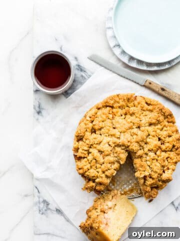 Apple crumb coffee cake ready to be served with cups of tea, plates and a serrated knife