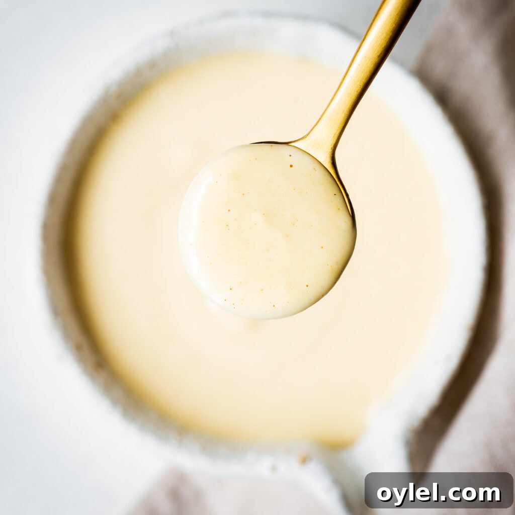 Lemon Tahini Sauce Recipe: 5 Flavor Variations 8 Creamy maple tahini dressing in a golden spoon viewed from above.