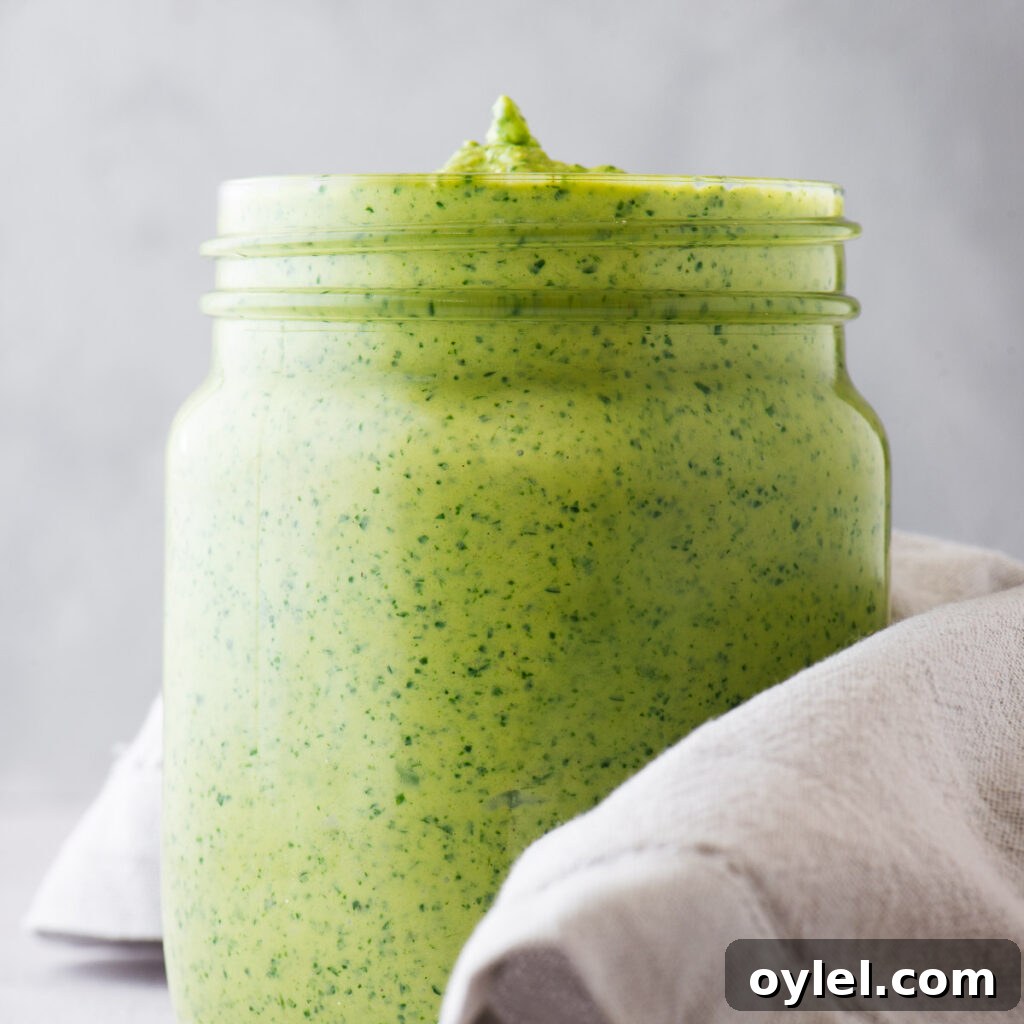 Lemon Tahini Sauce Recipe: 5 Flavor Variations 9 A glass jar with thick green tahini sauce.