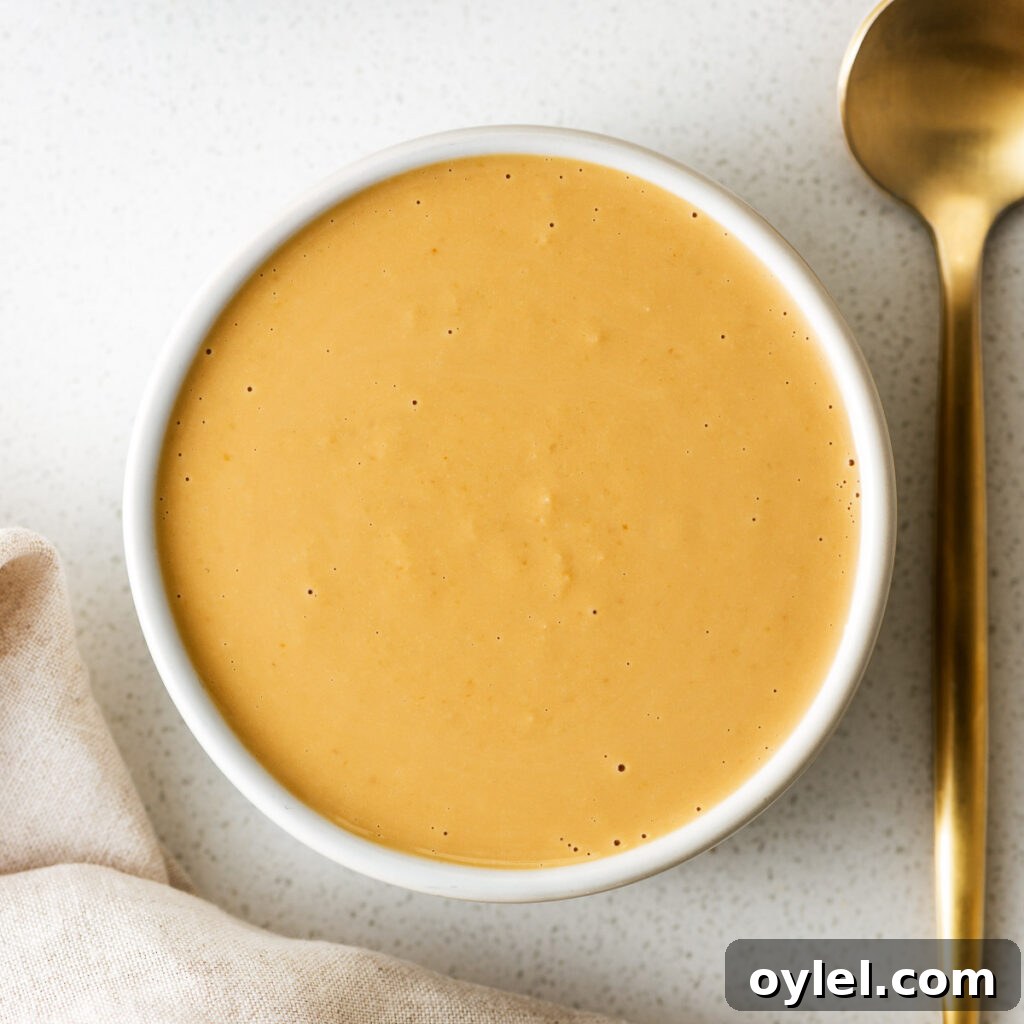 Lemon Tahini Sauce Recipe: 5 Flavor Variations 10 Tahini miso dressing in a small white bowl next to a golden teaspoon.