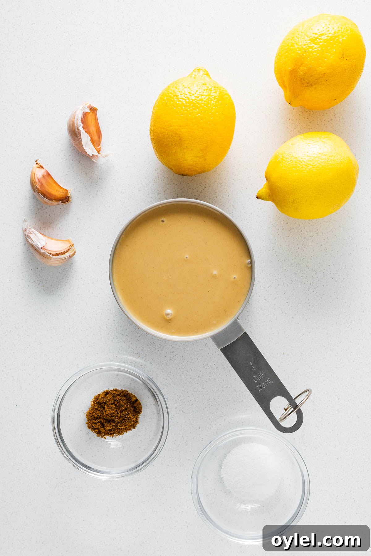 Lemon Tahini Sauce Recipe: 5 Flavor Variations 2 The simple ingredients for easy lemon tahini sauce viewed from above. This includes fresh lemons, tahini, garlic cloves, ground cumin and kosher salt.