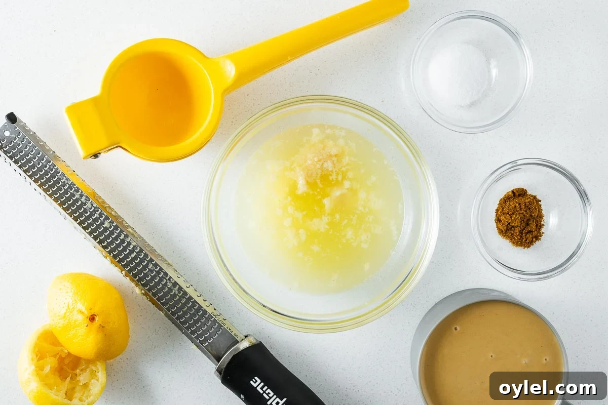 Lemon Tahini Sauce Recipe: 5 Flavor Variations 4 Grated garlic rests in fresh lemon juice in a glass bowl surrounded by the rest of the tahini sauce ingredients.