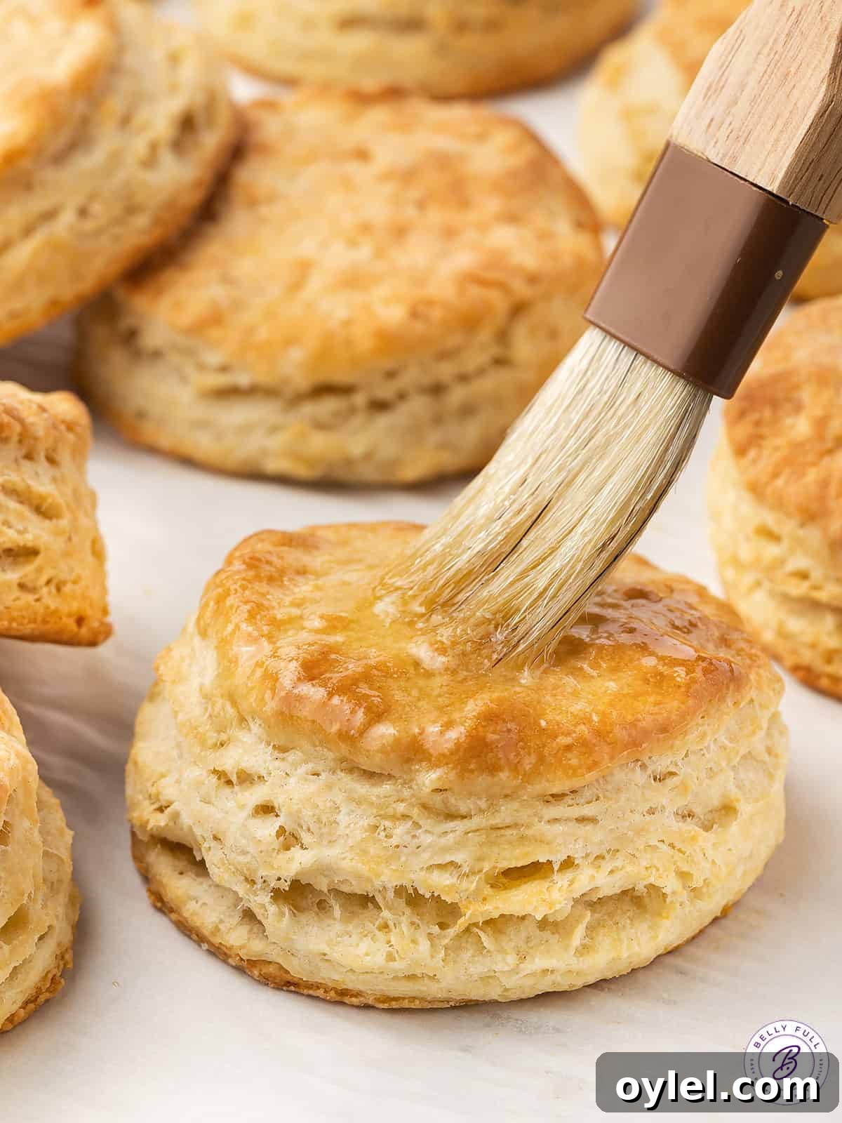 Butter being brushed on freshly baked homemade biscuits.