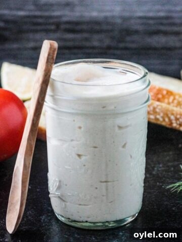 Small wooden spoon leaning against a jar of homemade vegan mayonnaise.