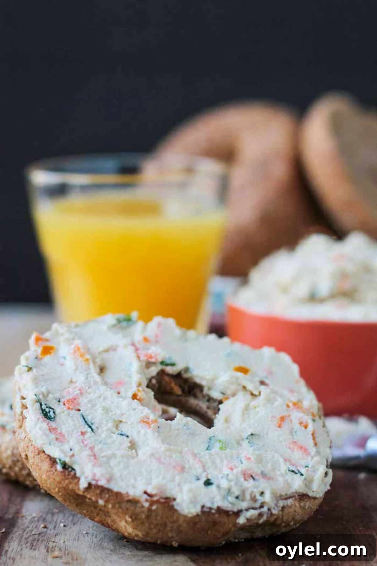 Close up for finely diced veggies in cream cheese on a bagel.