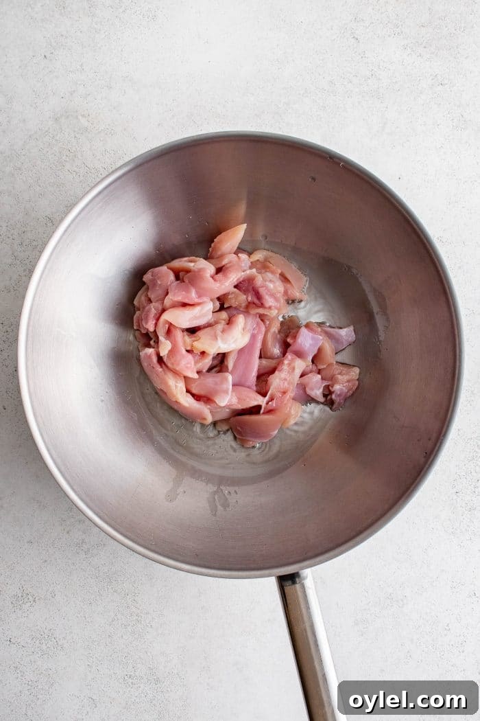 Raw chicken cooking in a large wok.