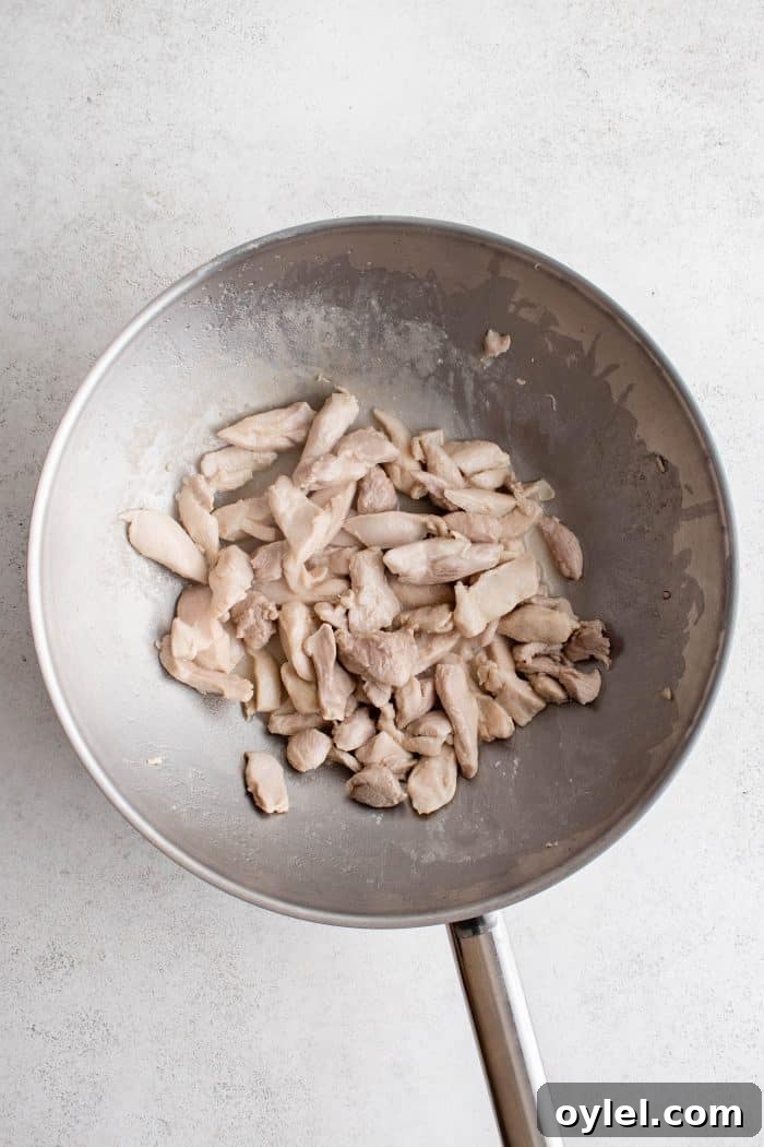 Large wok filled with cooked chicken.