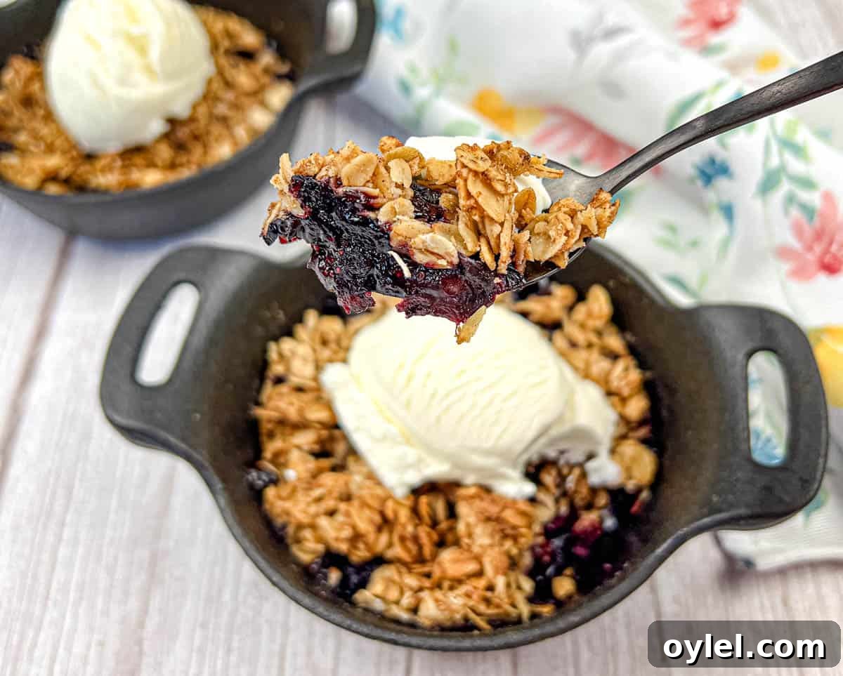 A spoon lifts a portion of Smoked Berry Crisp from a bowl.