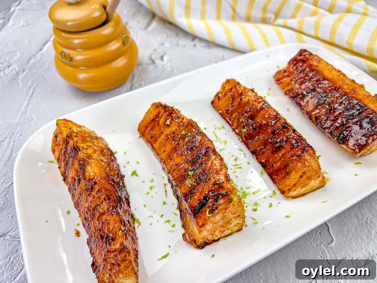 Four pieces of Grilled Pineapple With Buttery Lime Glaze on a white rectangular plate.