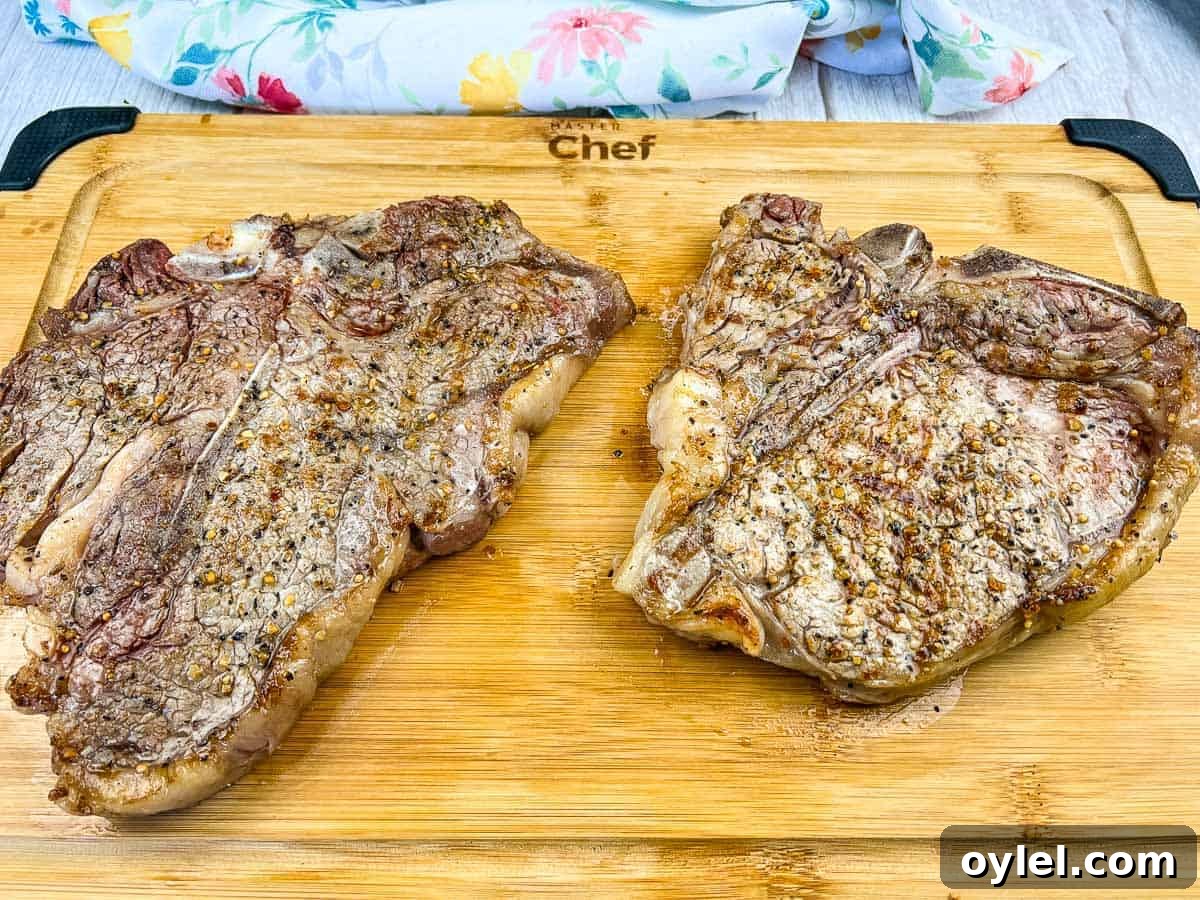 A grilled t-bone steak on a black platter.
