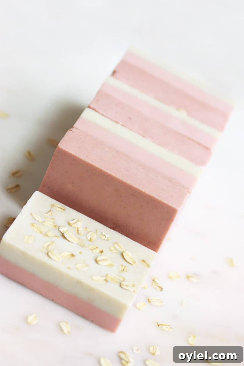 bars of pink and cream soap laying on a marble cutting board with oats sprinkled around