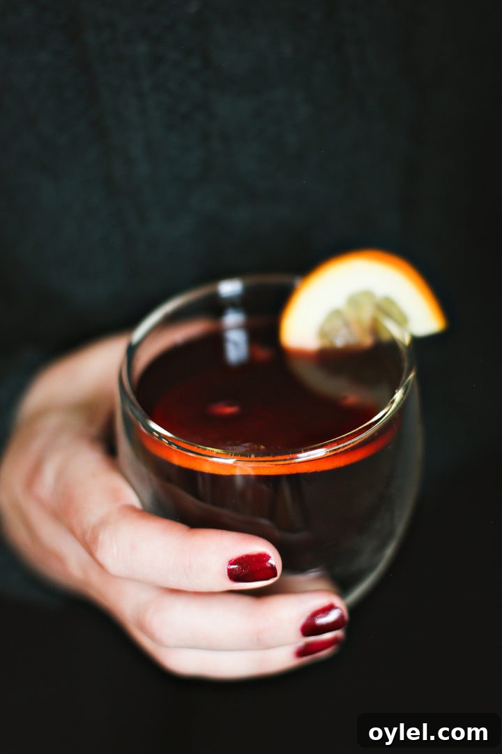 Cozy Spiced Apple Cider with Pomegranate 7 a woman holding a glass of hot spiced apple cider