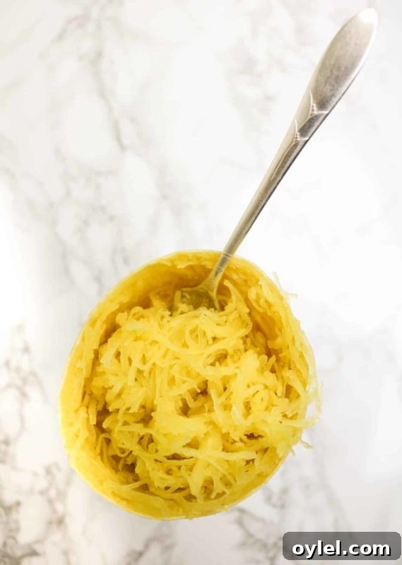 Spaghetti squash sitting on a marble table, fork in squash.