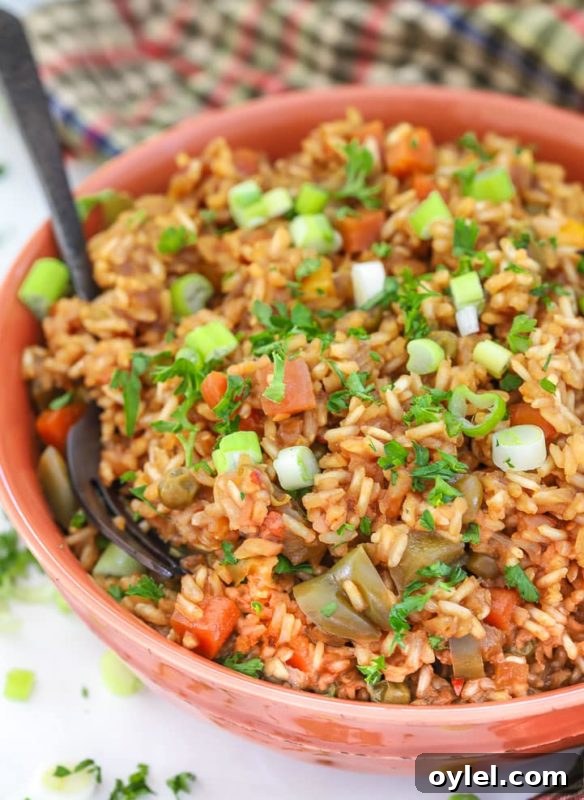 Red bowl containing Teriyaki Instant Pot Rice, topped with scallions, spoon in bowl.