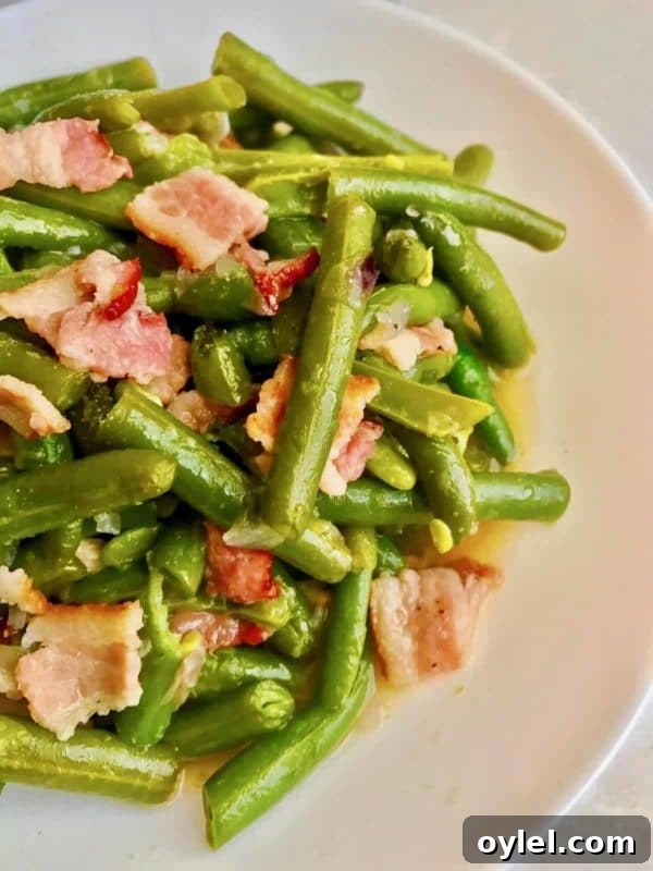 Cooked Green beans with bacon in a white plate cooked in an Instant Pot.